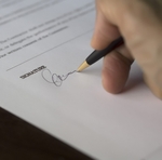 A hand with pen signing a legal document